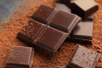 Delicious dark chocolate and cocoa powder on table, closeup