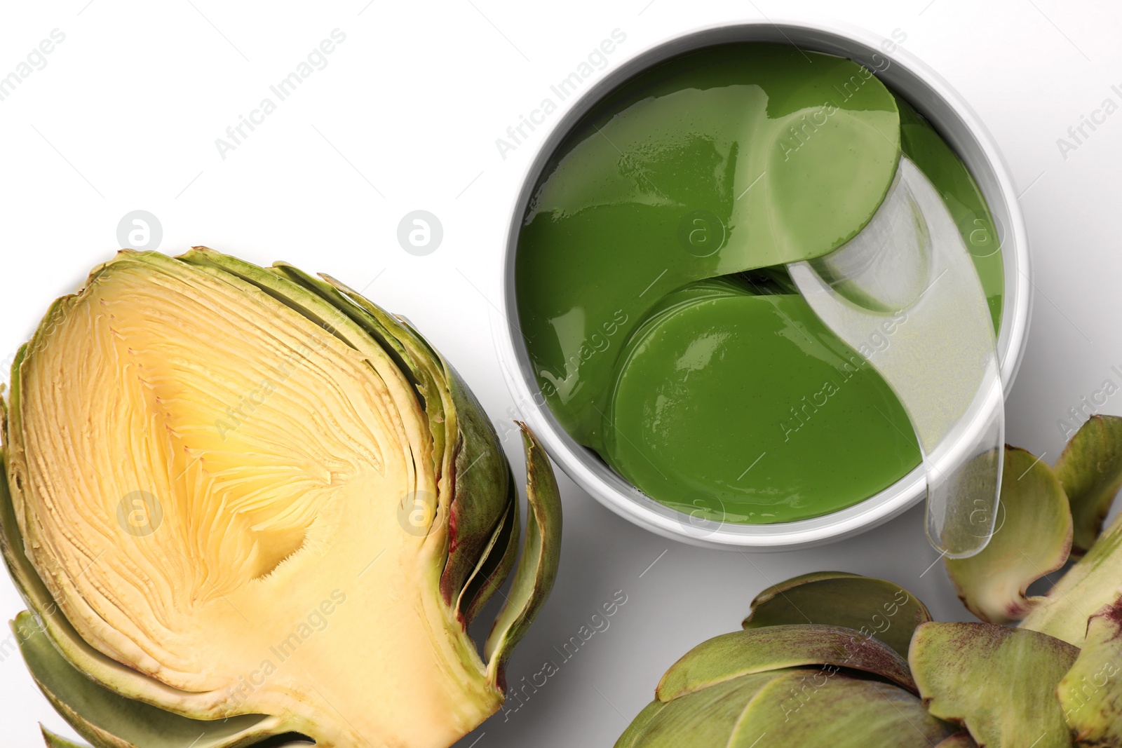 Photo of Package of under eye patches and artichokes on white background, top view. Cosmetic product