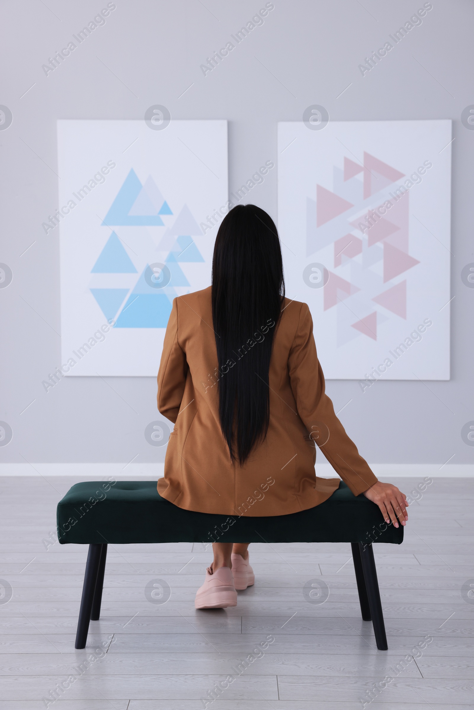 Photo of Young woman at exhibition in art gallery, back view