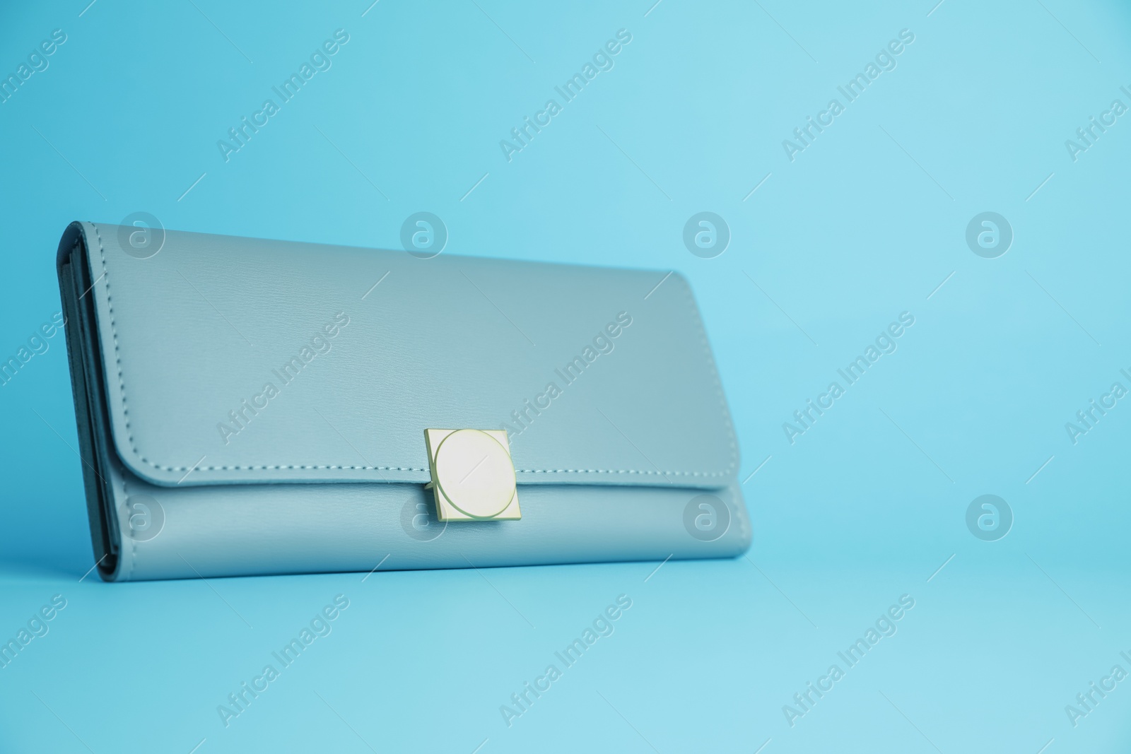 Photo of Stylish leather purse on light blue background. Space for text