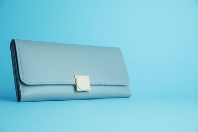 Stylish leather purse on light blue background. Space for text