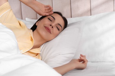 Photo of Woman awakening in comfortable bed with white linens
