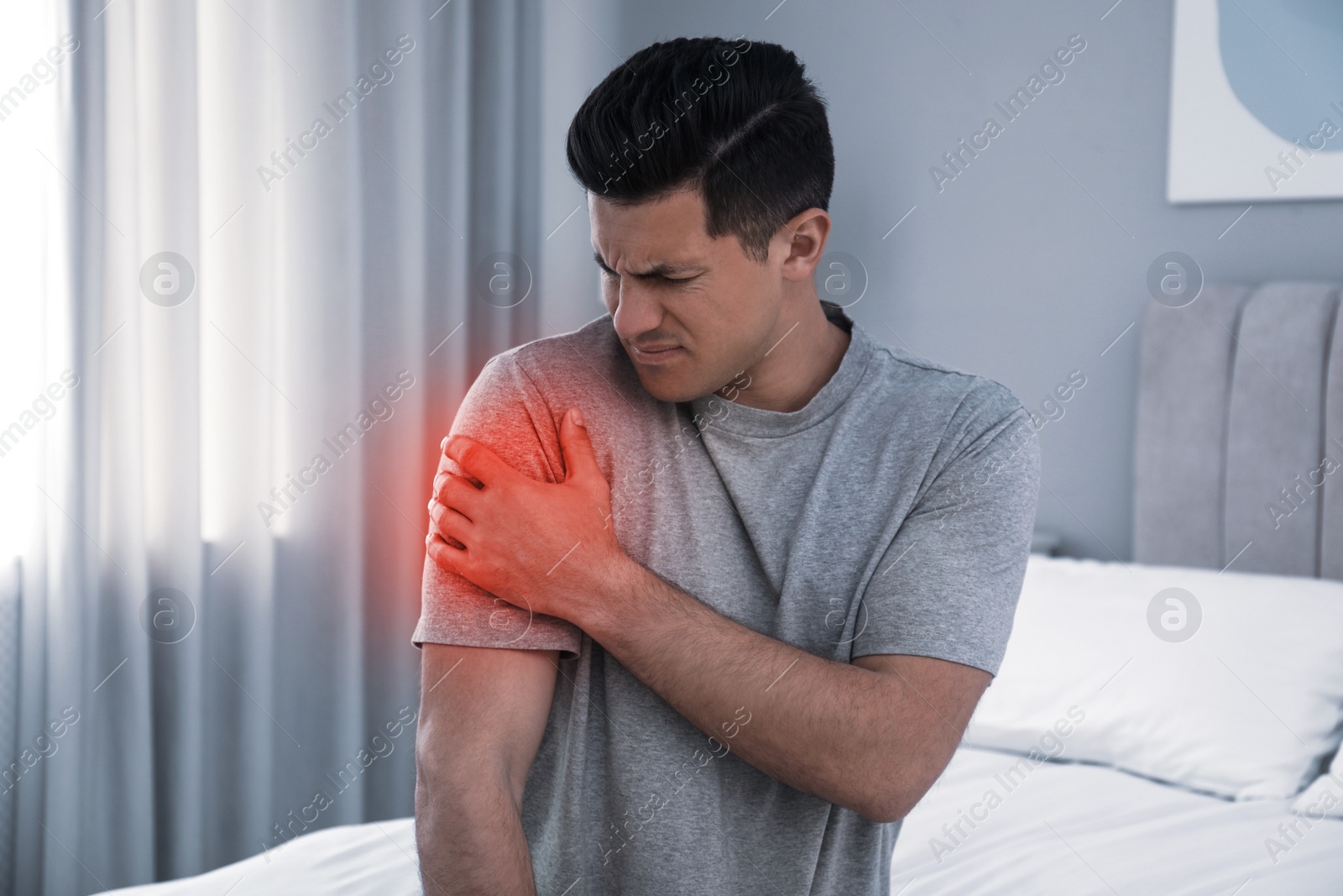 Image of Man suffering from shoulder pain on bed at home
