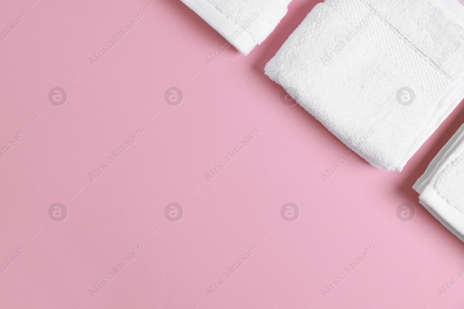 Photo of Soft folded white towels on violet background, flat lay. Space for text