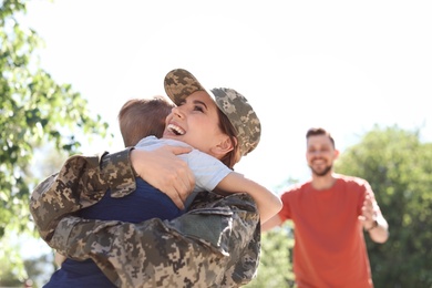 Photo of Female soldier hugging with her son outdoors. Military service