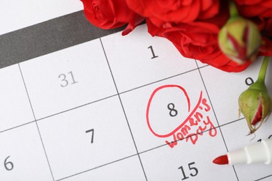 Photo of Roses and red marker on calendar near date 8th of March, above view. International Women's Day