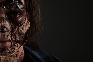 Scary zombie on dark background, closeup with space for text. Halloween monster