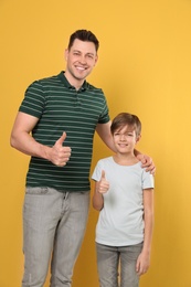 Portrait of dad and his son on color background