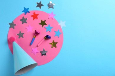 Photo of Party hat, confetti and blowers on light blue background, flat lay. Space for text