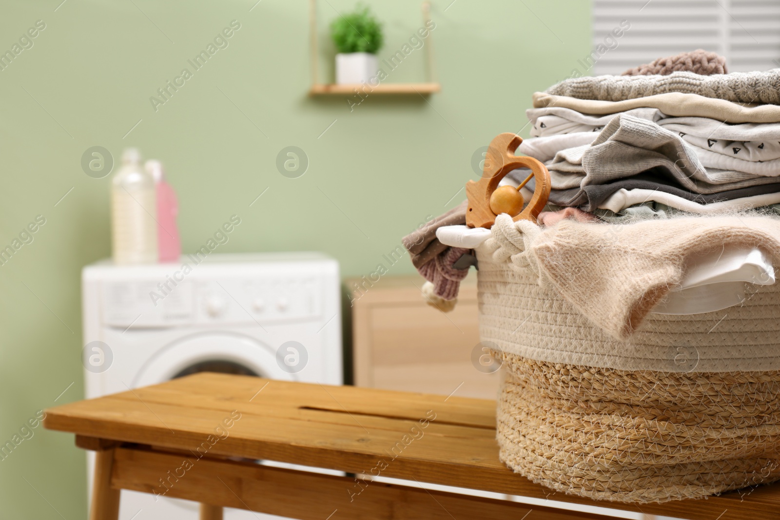 Photo of Laundry basket with baby clothes and toy on table in bathroom, closeup. Space for text