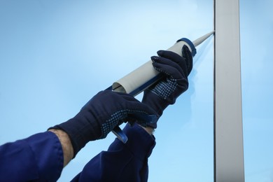 Photo of Construction worker sealing window with caulk, closeup
