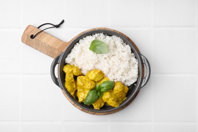 Photo of Delicious rice and chicken with curry sauce on white tiled table, top view