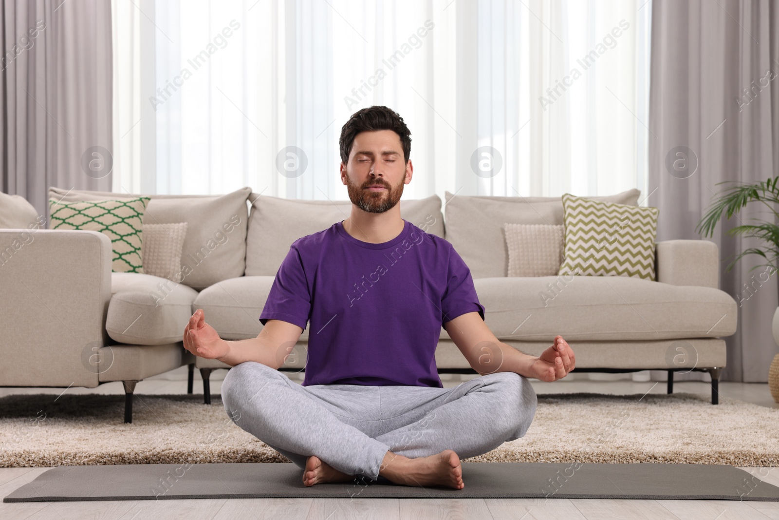 Photo of Man meditating on yoga mat at home. Harmony and zen