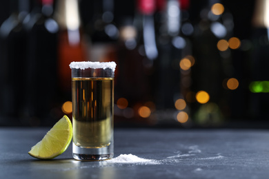 Photo of Mexican Tequila shot with lime and salt on bar counter. Space for text