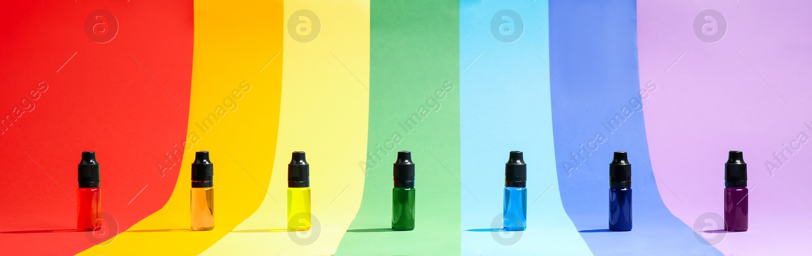 Photo of Bottles with different food coloring on rainbow background