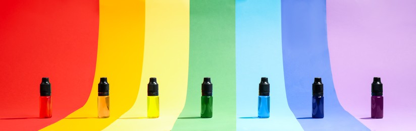 Bottles with different food coloring on rainbow background