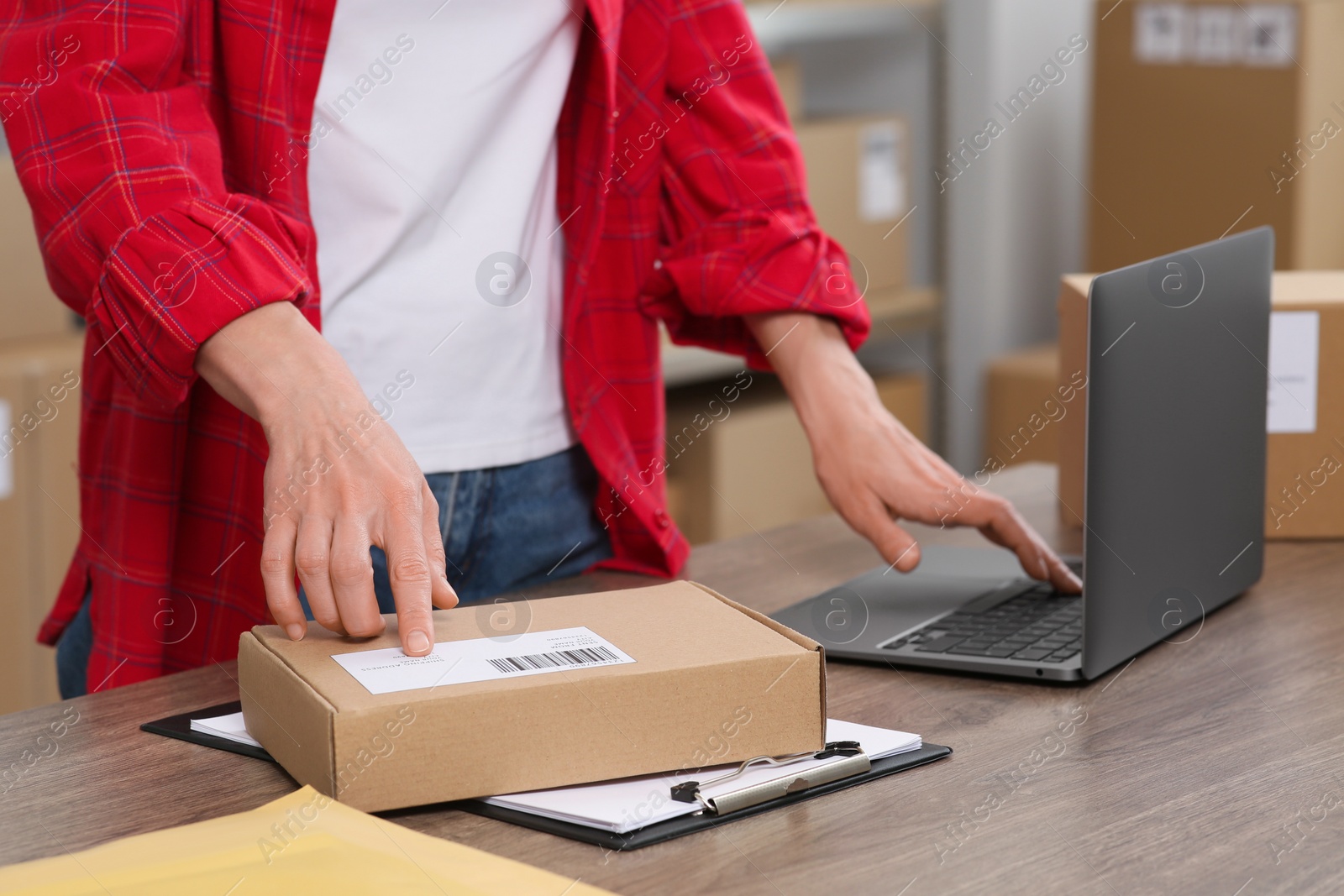 Photo of Seller with laptop and parcels working in office, closeup. Online store