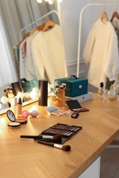 Different cosmetic products on wooden dressing table in makeup room