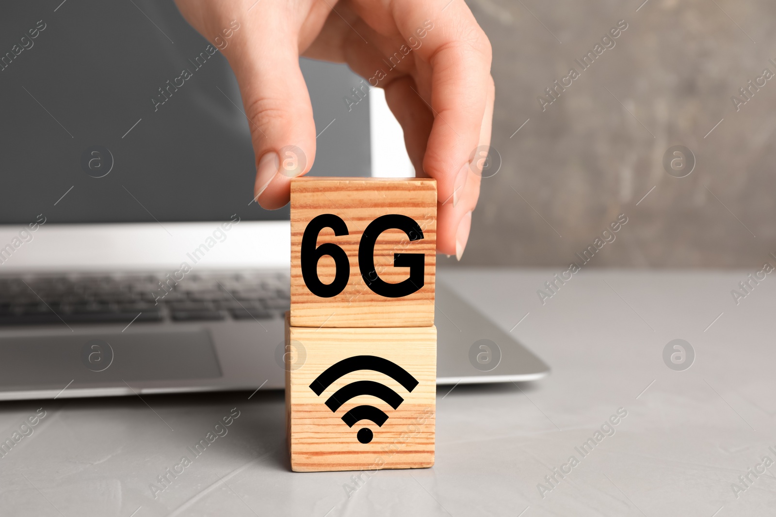 Photo of 6G technology, Internet concept. Woman stacking wooden cubes on light grey office table, closeup