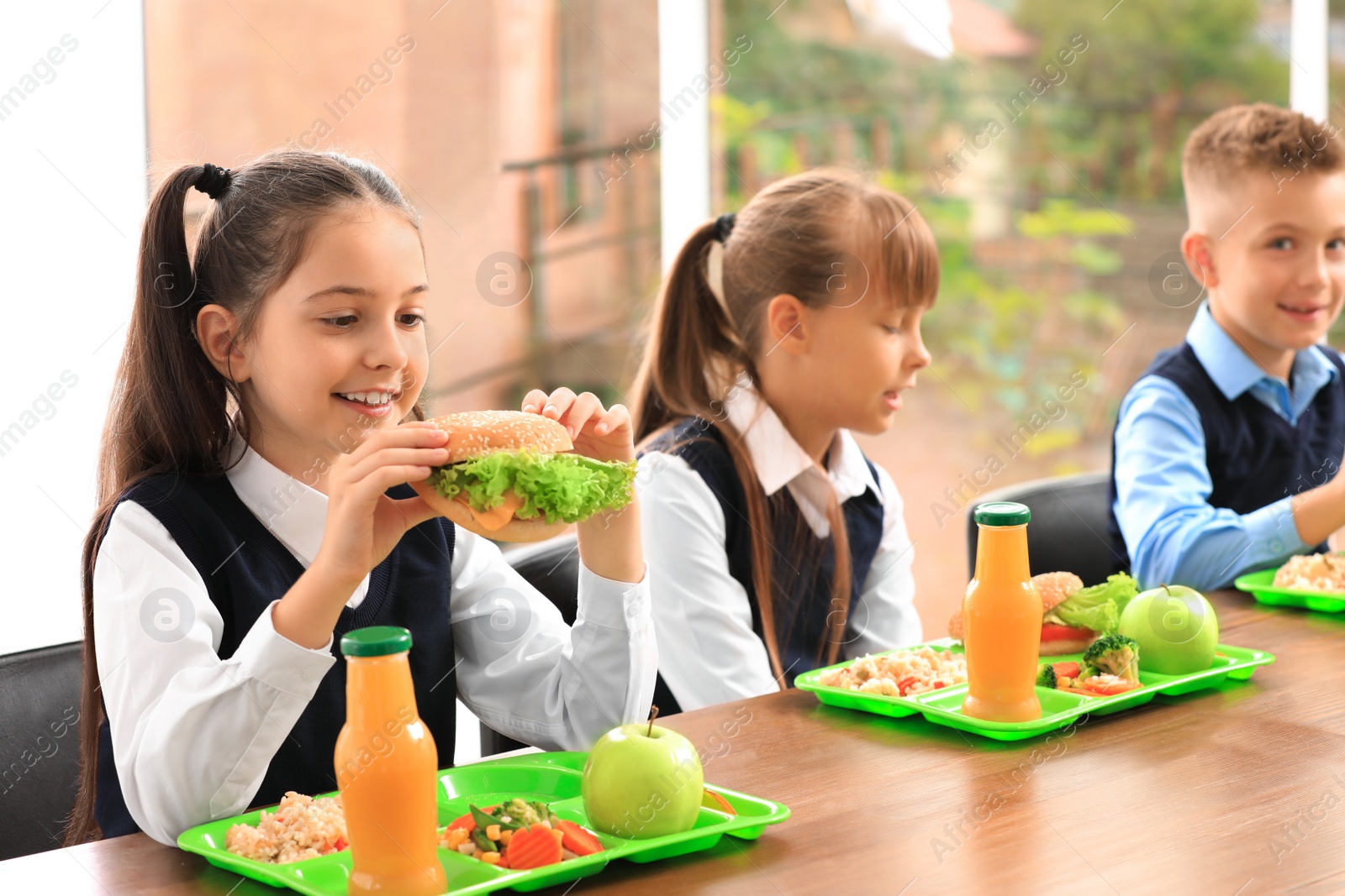 Photo of Happy children at table with healthy food in school canteen