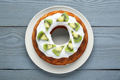 Photo of Homemade yogurt cake with kiwi and cream on grey wooden table, top view