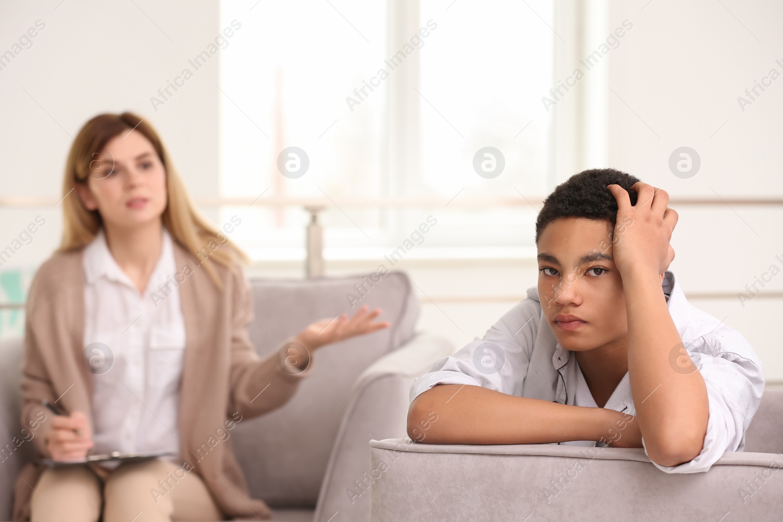 Photo of Young female psychologist working with teenage boy in office