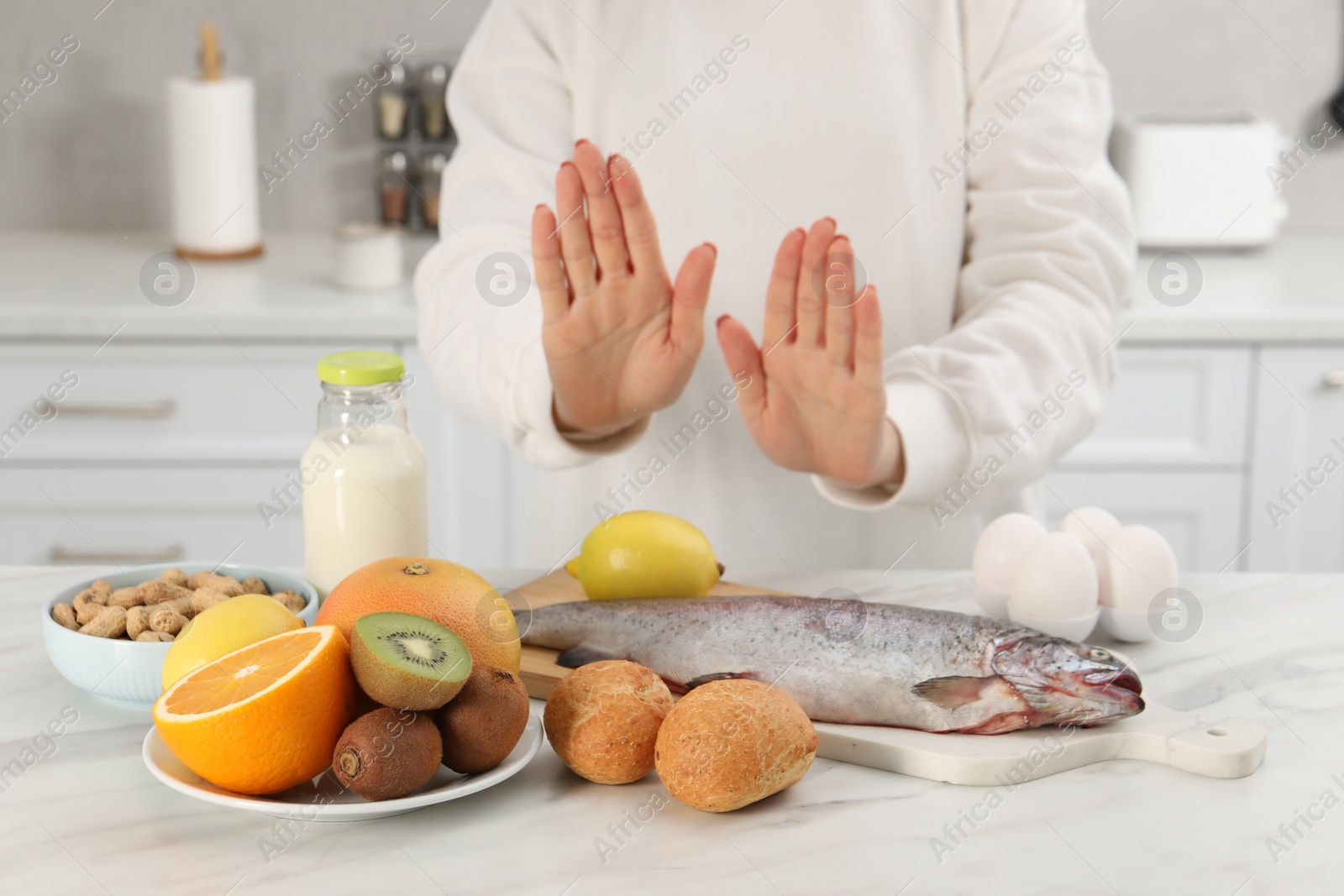 Photo of Woman suffering from food allergies refusing eat different fresh products at light table indoors, closeup