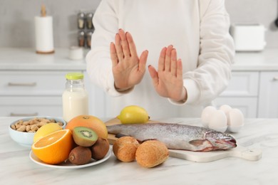 Photo of Woman suffering from food allergies refusing eat different fresh products at light table indoors, closeup