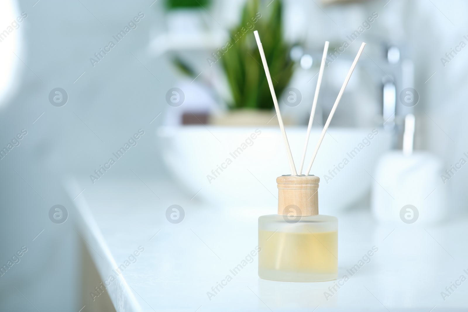 Photo of Aromatic reed air freshener on table indoors. Space for text