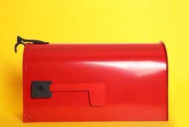 Photo of Closed red letter box on yellow background, closeup