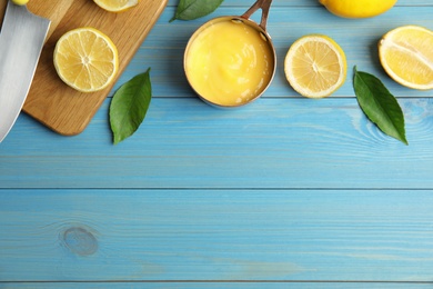 Delicious lemon curd and fresh fruits on light blue wooden table, flat lay. Space for text