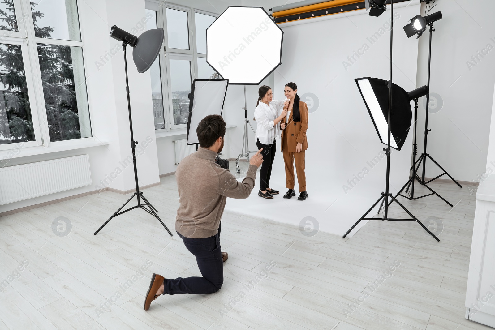 Photo of Professional photographer and assistant working with beautiful model in modern photo studio