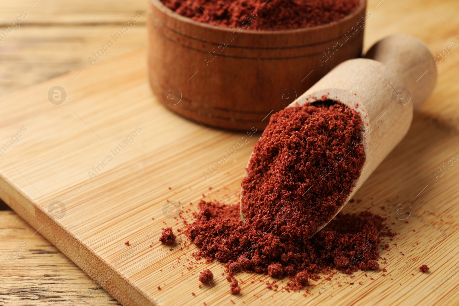 Photo of Scoop and bowl with cranberry powder on wooden table, closeup. Space for text