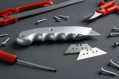 Photo of Utility knife with blades among other tools on grey background