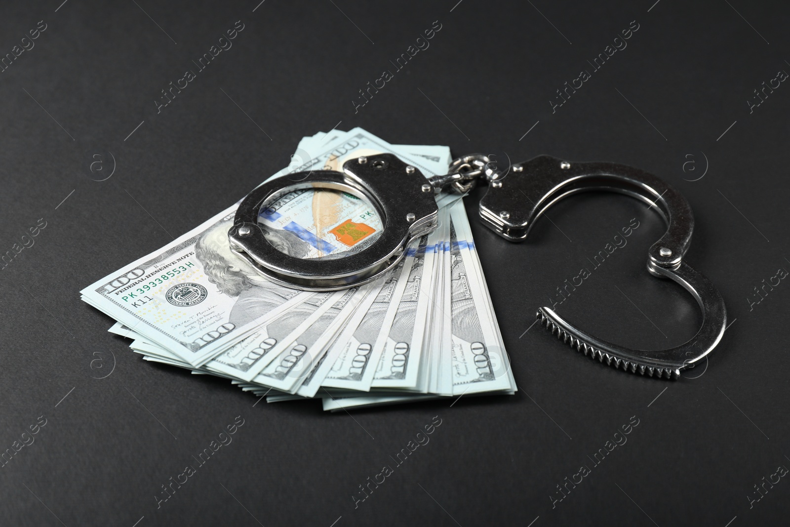 Photo of Dollars and metal handcuffs on grey table