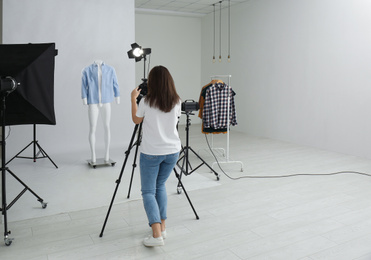 Professional photographer taking picture of ghost mannequin with modern clothes in photo studio