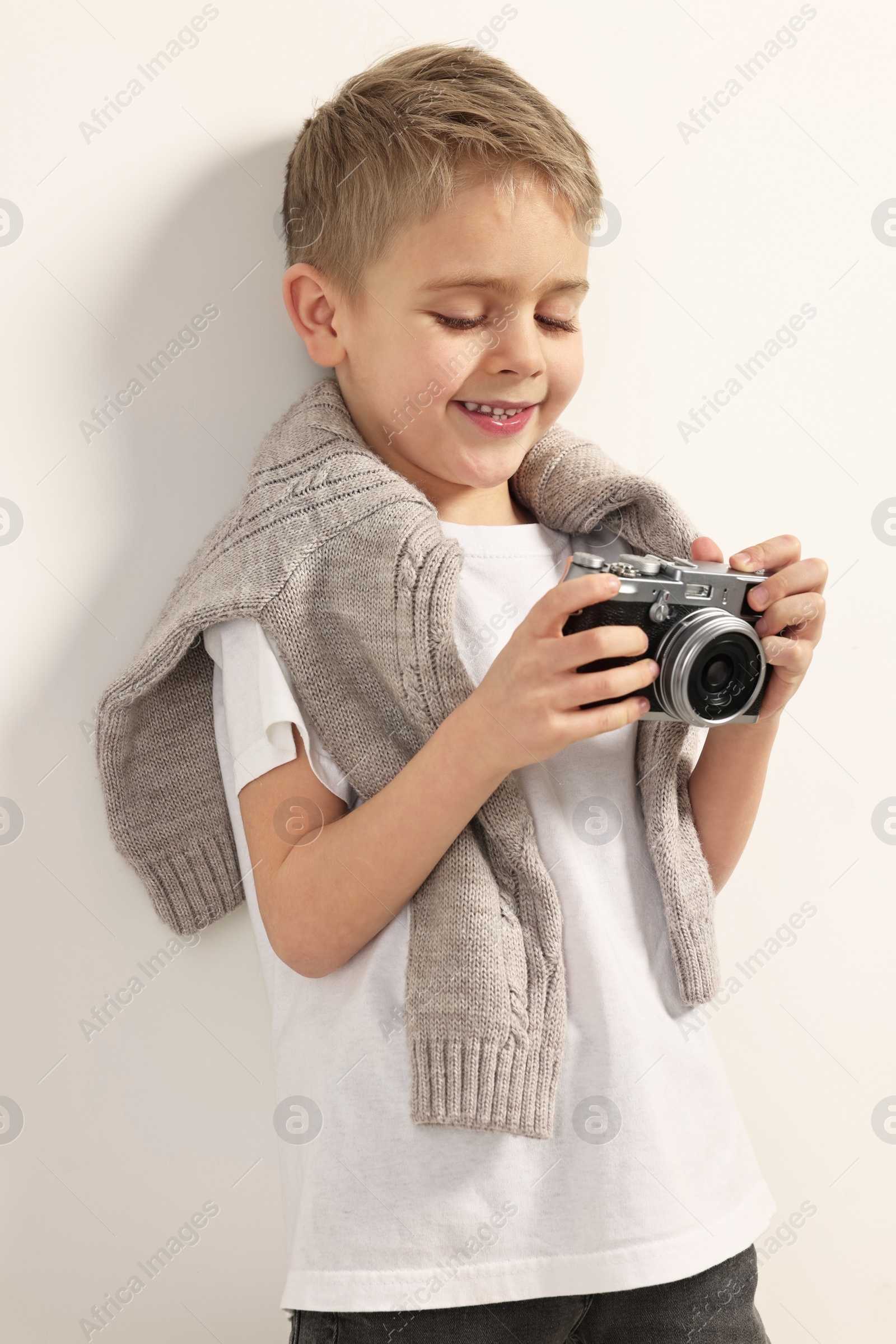 Photo of Fashion concept. Stylish boy with vintage camera on white background