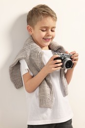 Photo of Fashion concept. Stylish boy with vintage camera on white background