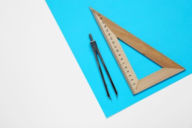 Photo of Triangle ruler, paper sheet and compass on white background, flat lay
