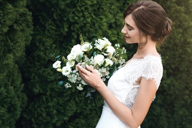 Photo of Gorgeous bride in beautiful wedding dress with bouquet outdoors