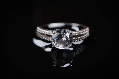 Photo of Luxury jewelry. Elegant ring on black mirror surface, closeup