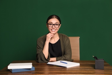 Photo of Portrait of young teacher at table against green background