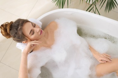 Beautiful woman enjoying bubble bath at home, above view