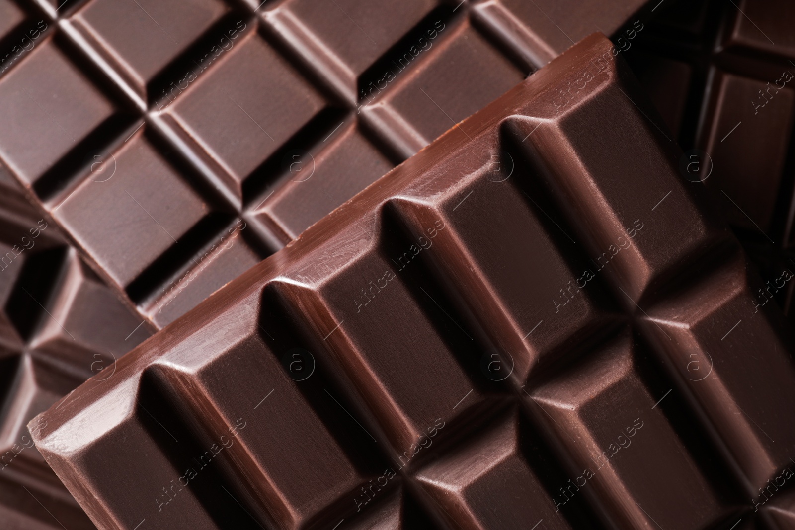 Photo of Many delicious dark chocolate bars as background, top view