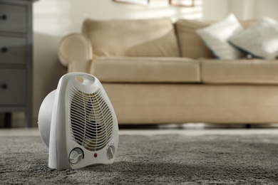 Photo of Modern electric fan heater in living room. Space for text