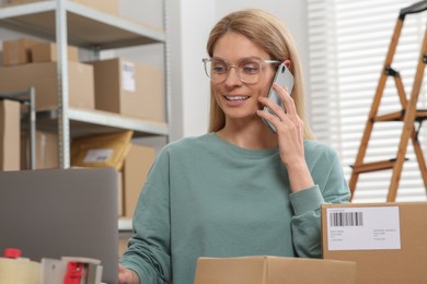 Photo of Seller talking on phone while working in office. Online store