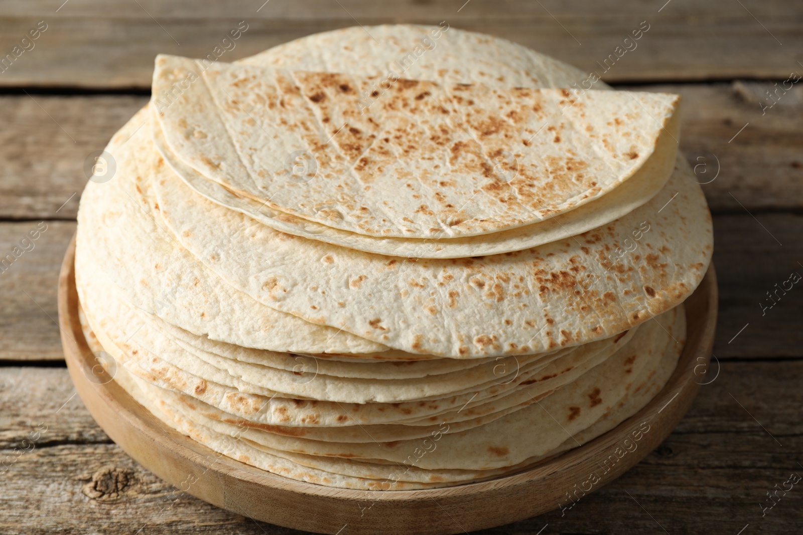 Photo of Stack of tasty homemade tortillas on wooden table