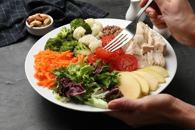 Photo of Balanced diet and healthy foods. Woman eating dinner at black table, closeup