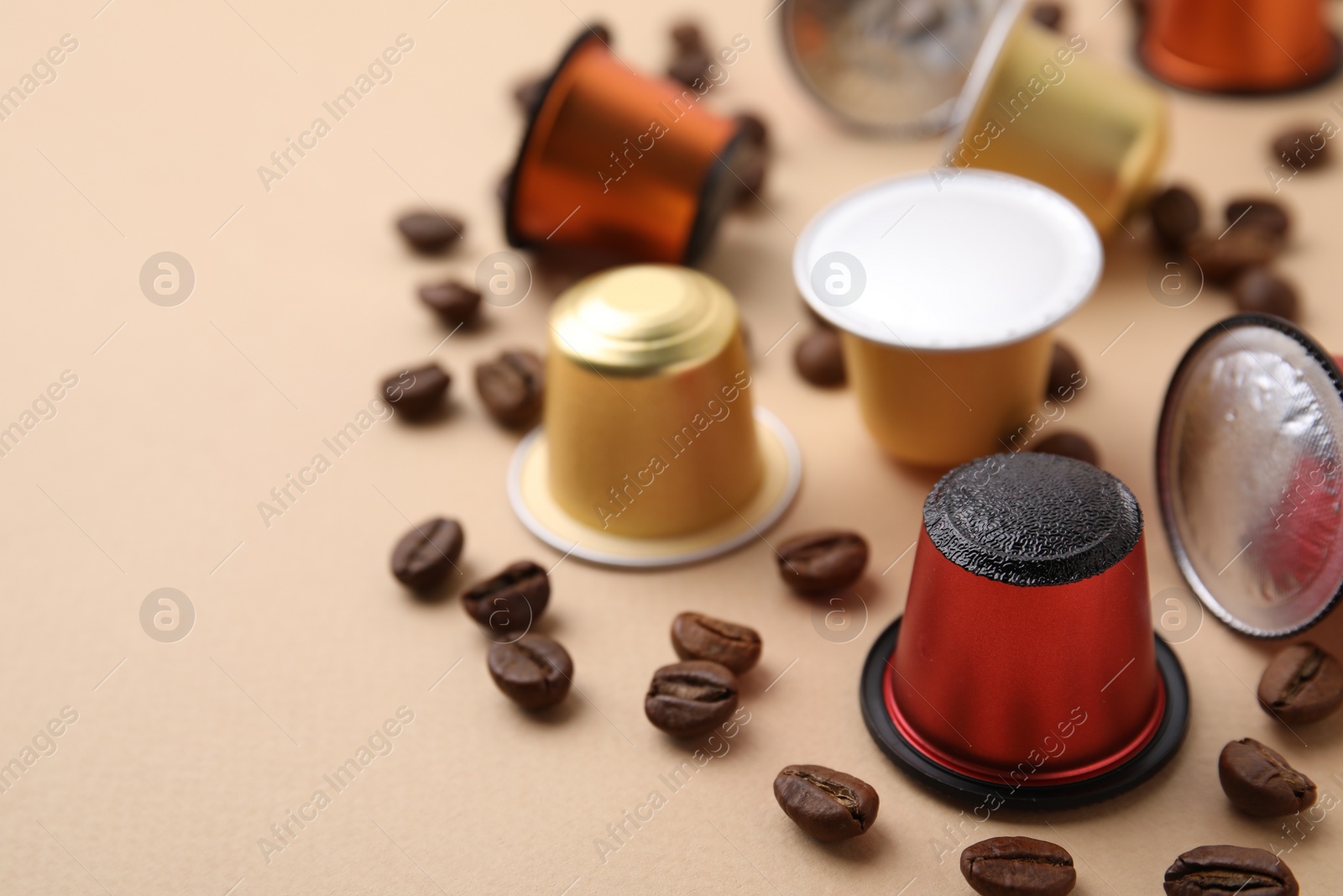 Photo of Many coffee capsules and beans on beige background, closeup. Space for text