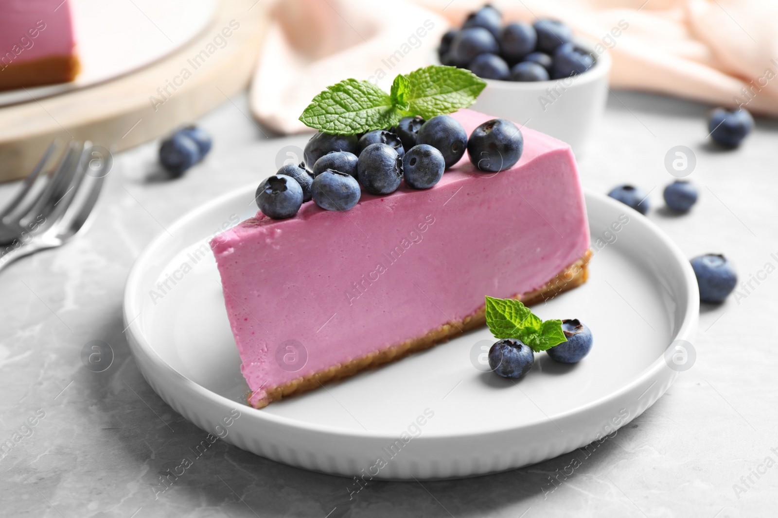 Photo of Plate with piece of tasty blueberry cake on light table